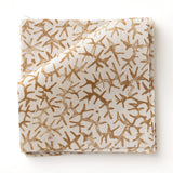 Fabric swatch with small scale coral design in warm tan on white. 