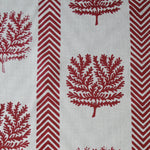 Detail of fabric in a in a tree and chevron stripe print in red on a white field.