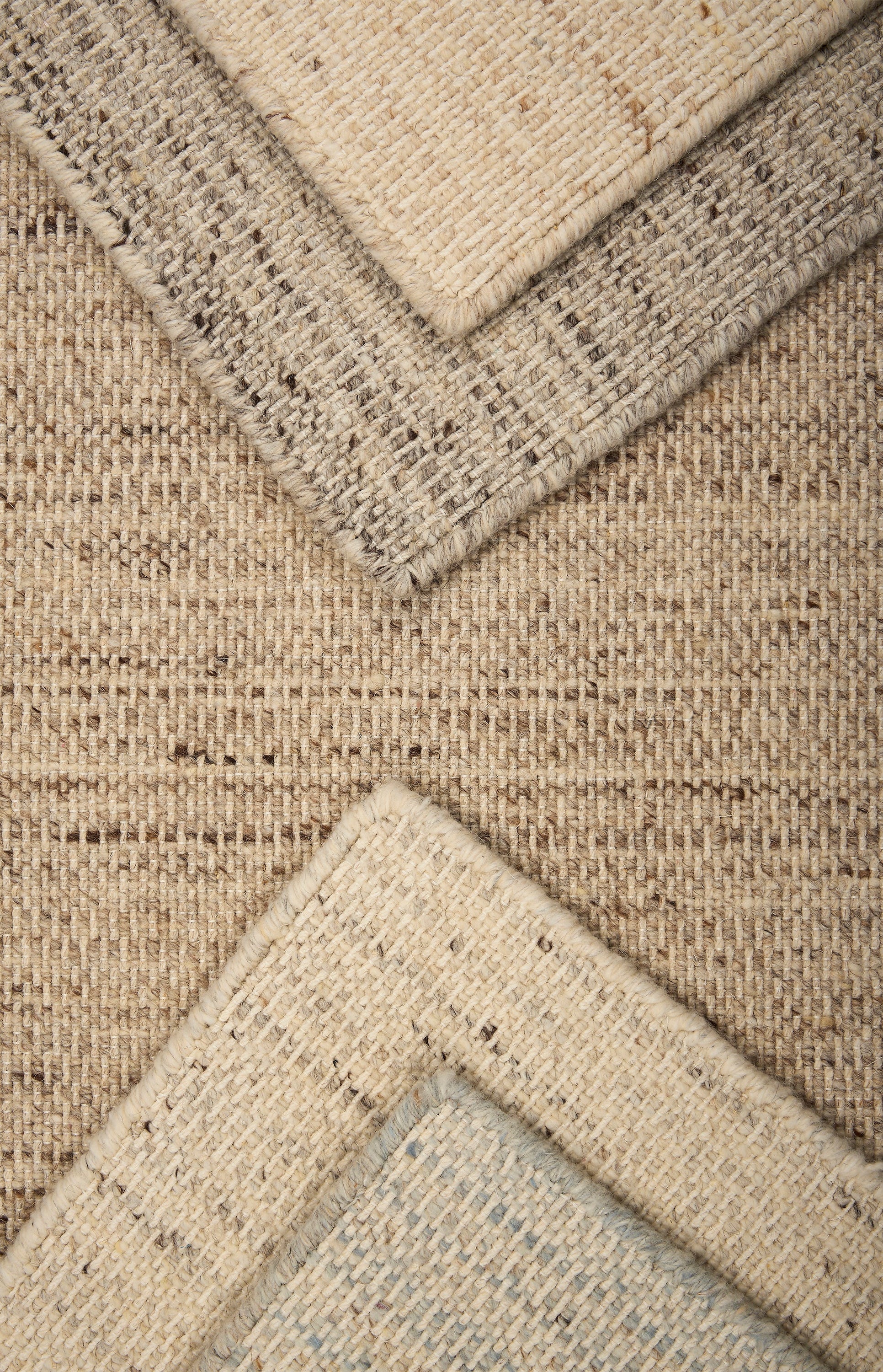 Stack of strié textural broadloom carpet in a range of neutral tones.