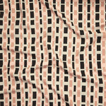 Close up of printed linen with graphic plaid pattern in shades of pink, beige and black.