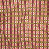 Close up of printed linen with graphic plaid pattern in pink, magenta, tan and olive green. 