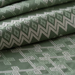 Green fabric with geometric pattern, lightly folded.