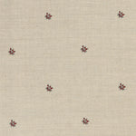 Detail of a printed linen fabric in a repeating small-scale flower pattern in red and gray on a cream field.