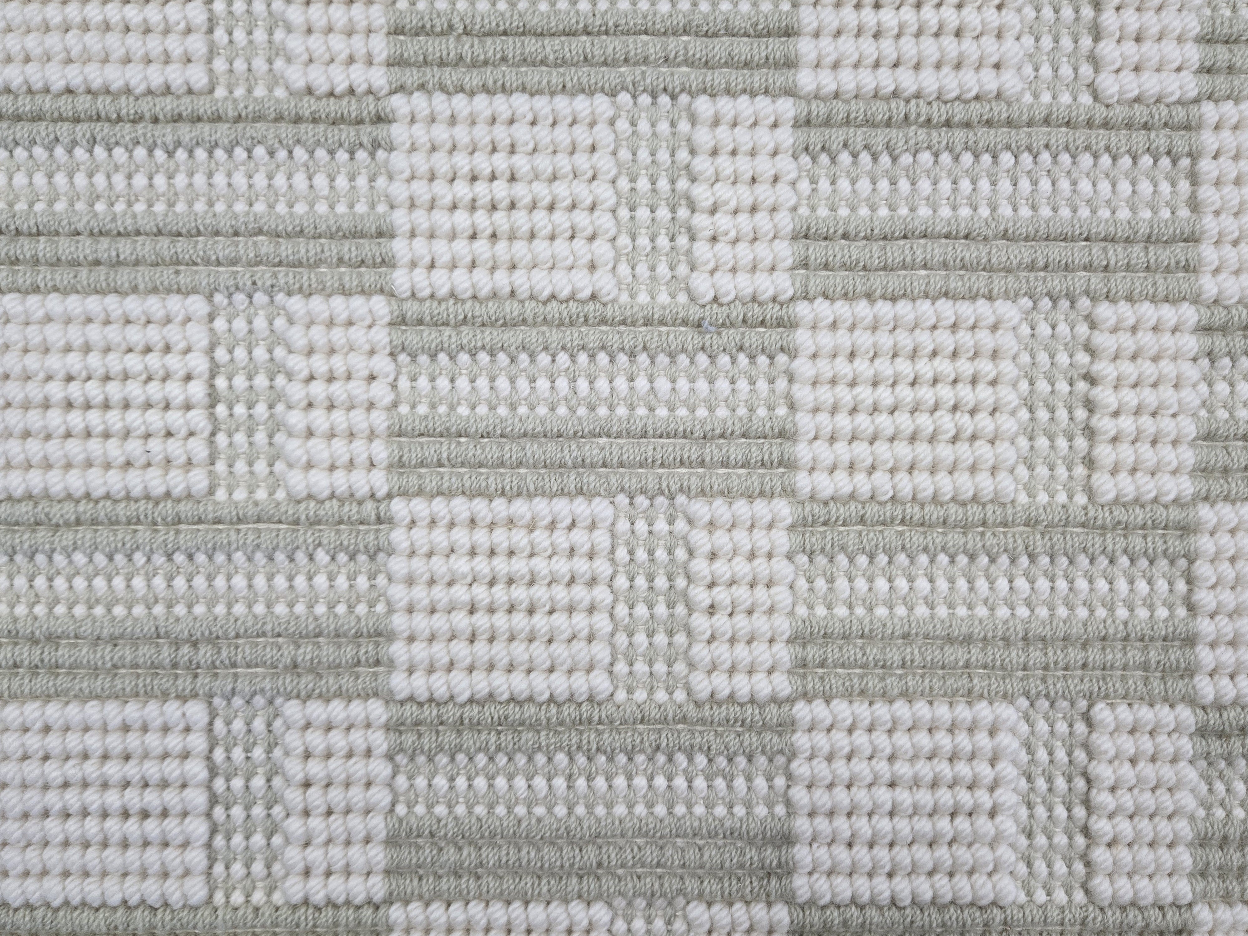 Broadloom carpet in a complex checkerboard pattern in ivory and pastel sage green.