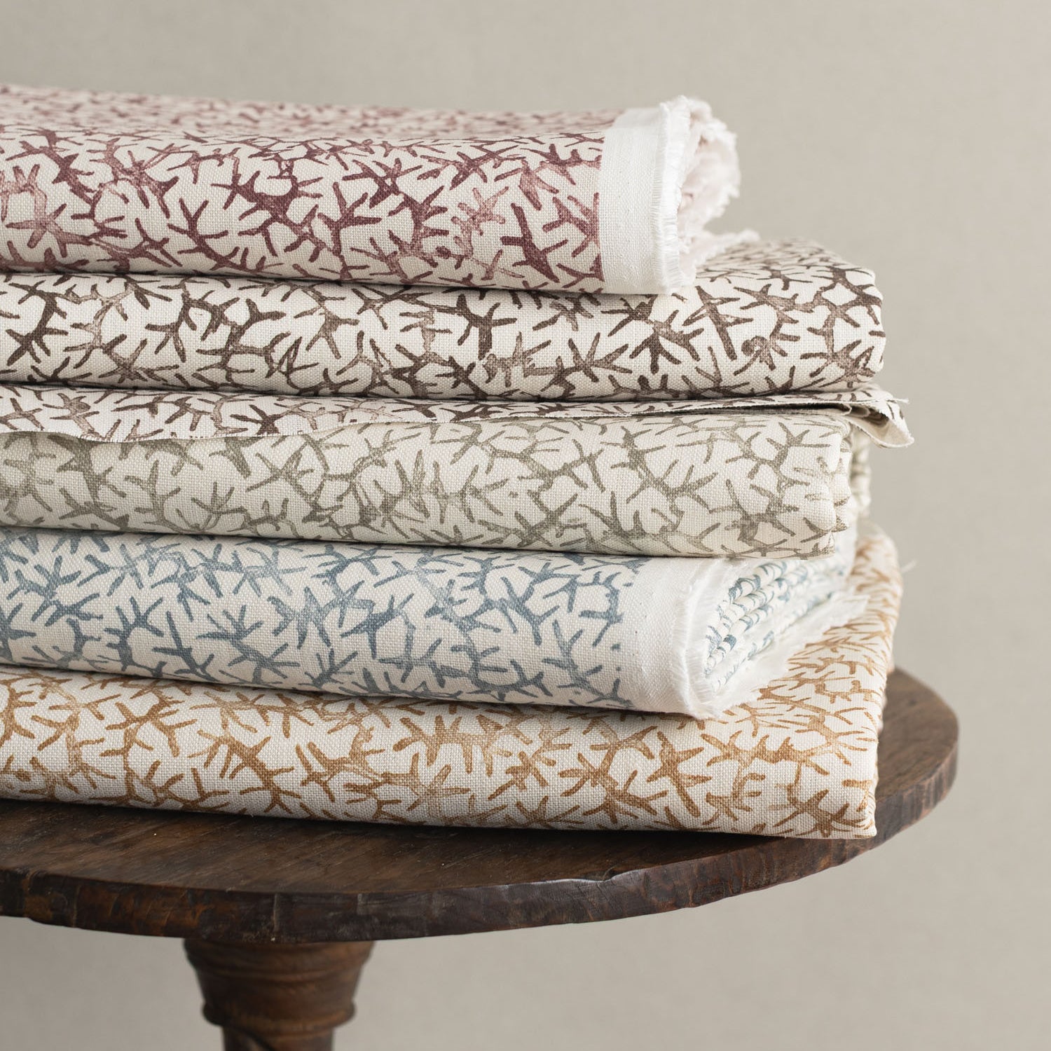 Wooden stool with folded fabrics in watercolor coral design in various colors. 