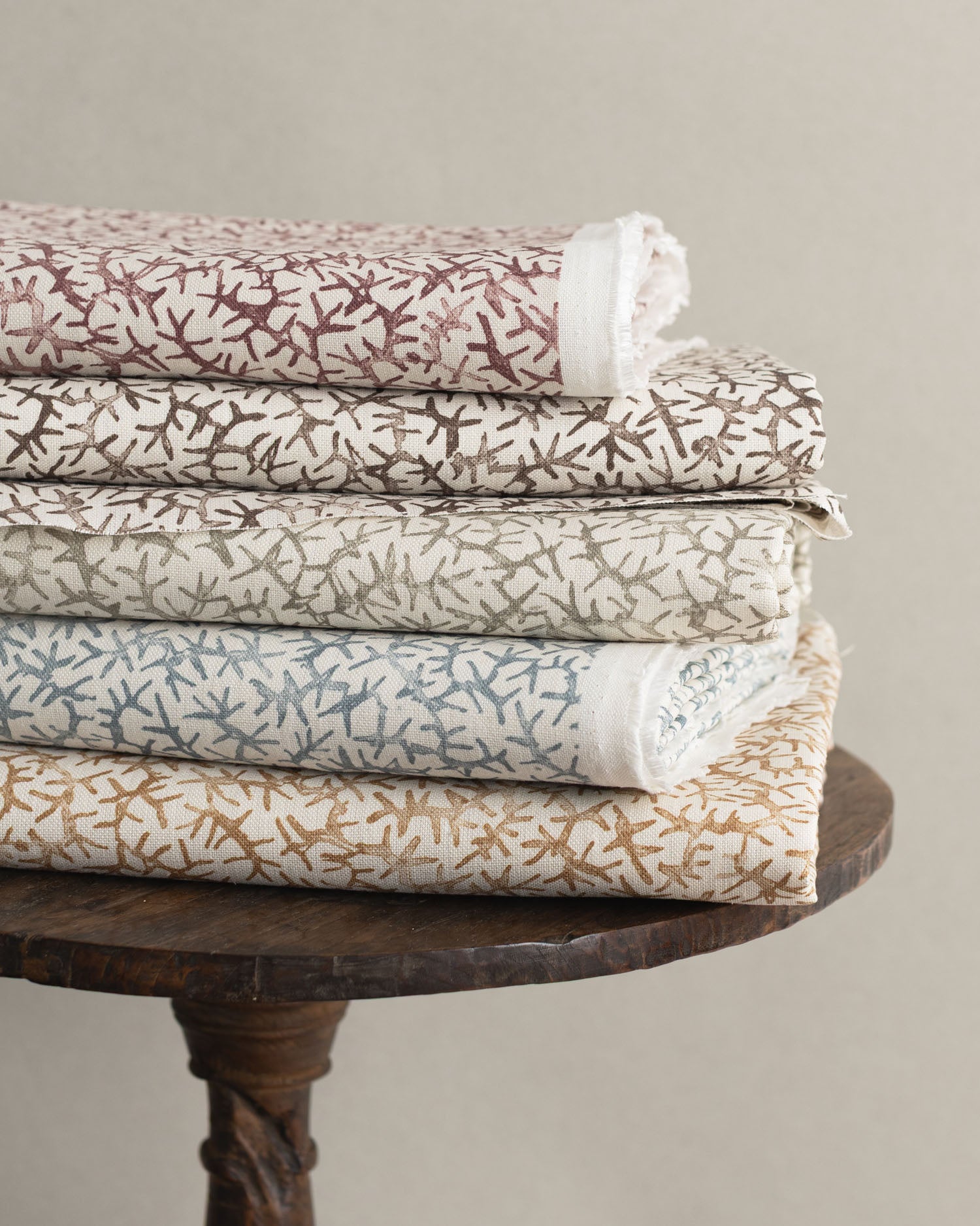 Wooden stool with folded fabrics in watercolor coral design in various colors. 