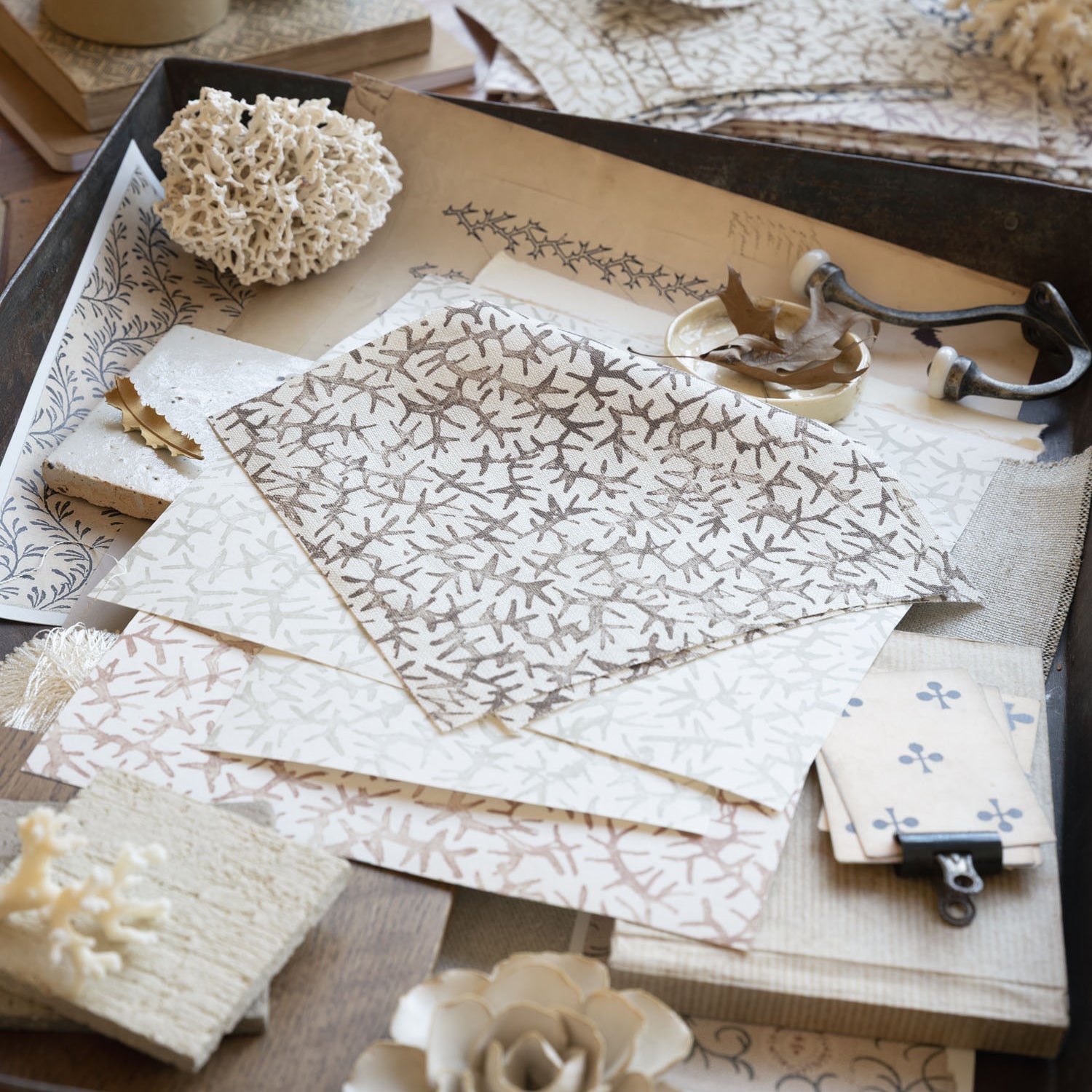 Desk scene with layered swatches of fabrics and natural specimens. 