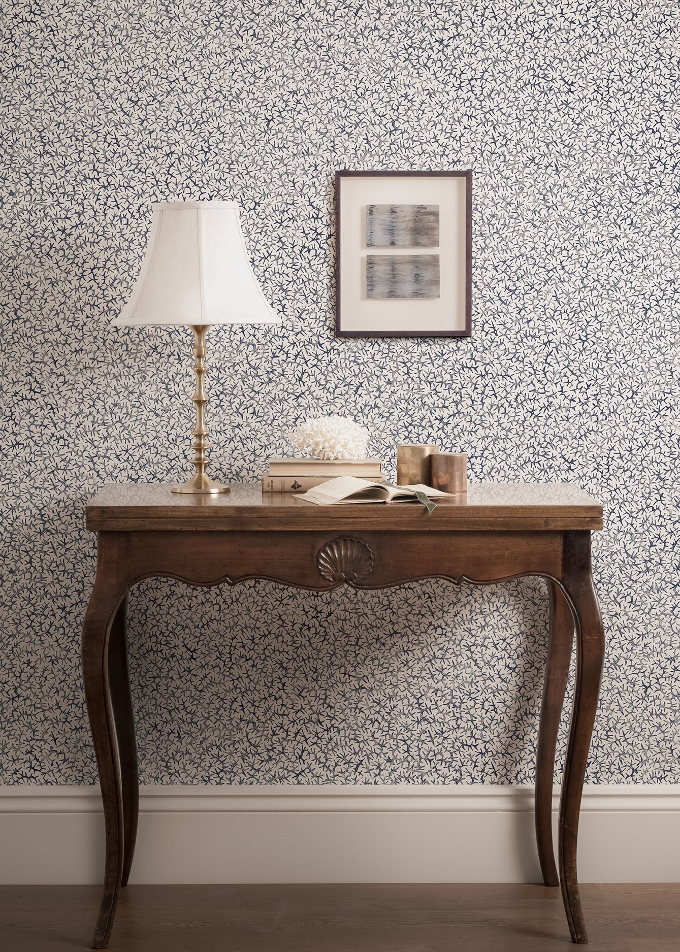 Wooden table with vintage accessories against a blue and white wallpaper wall. 