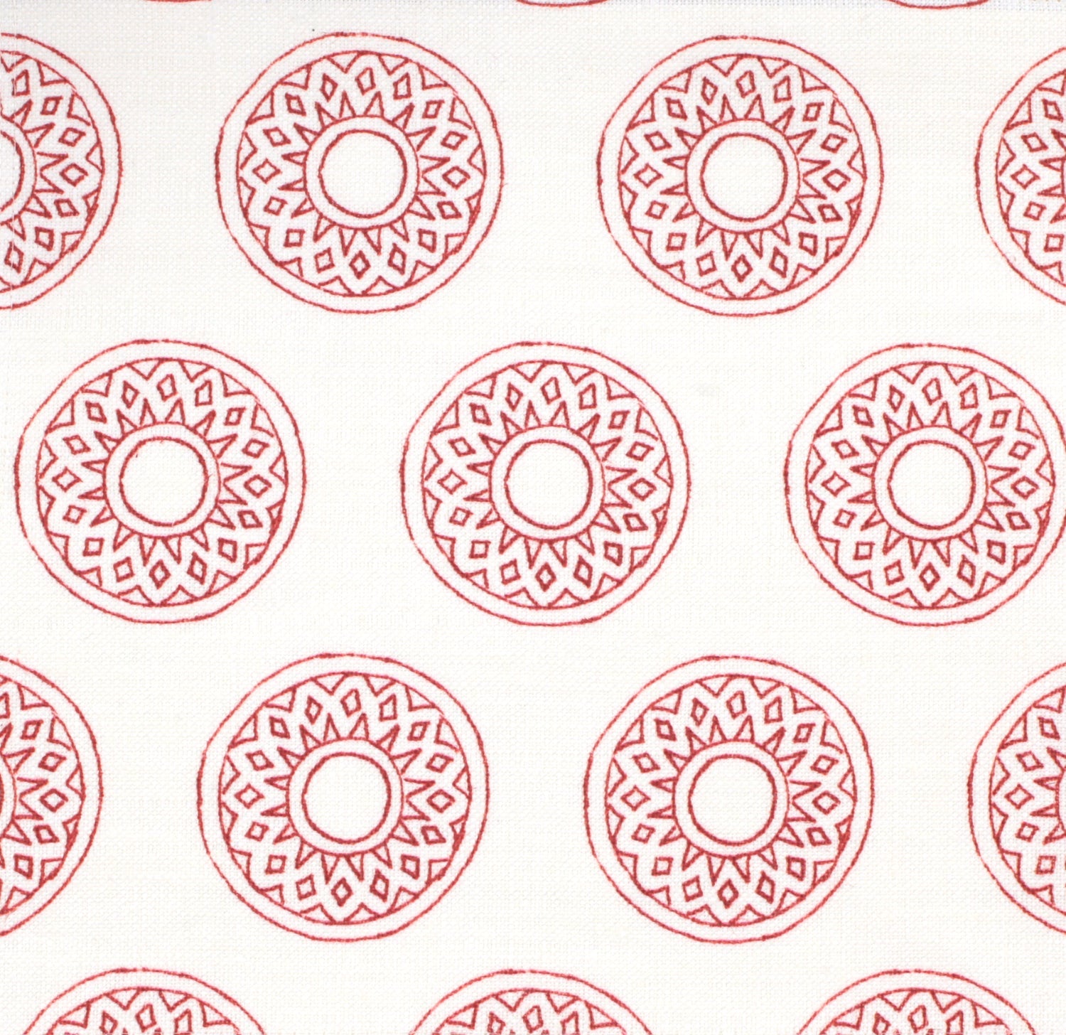 Detail of fabric in a repeating circular geometric print in red on a white field.