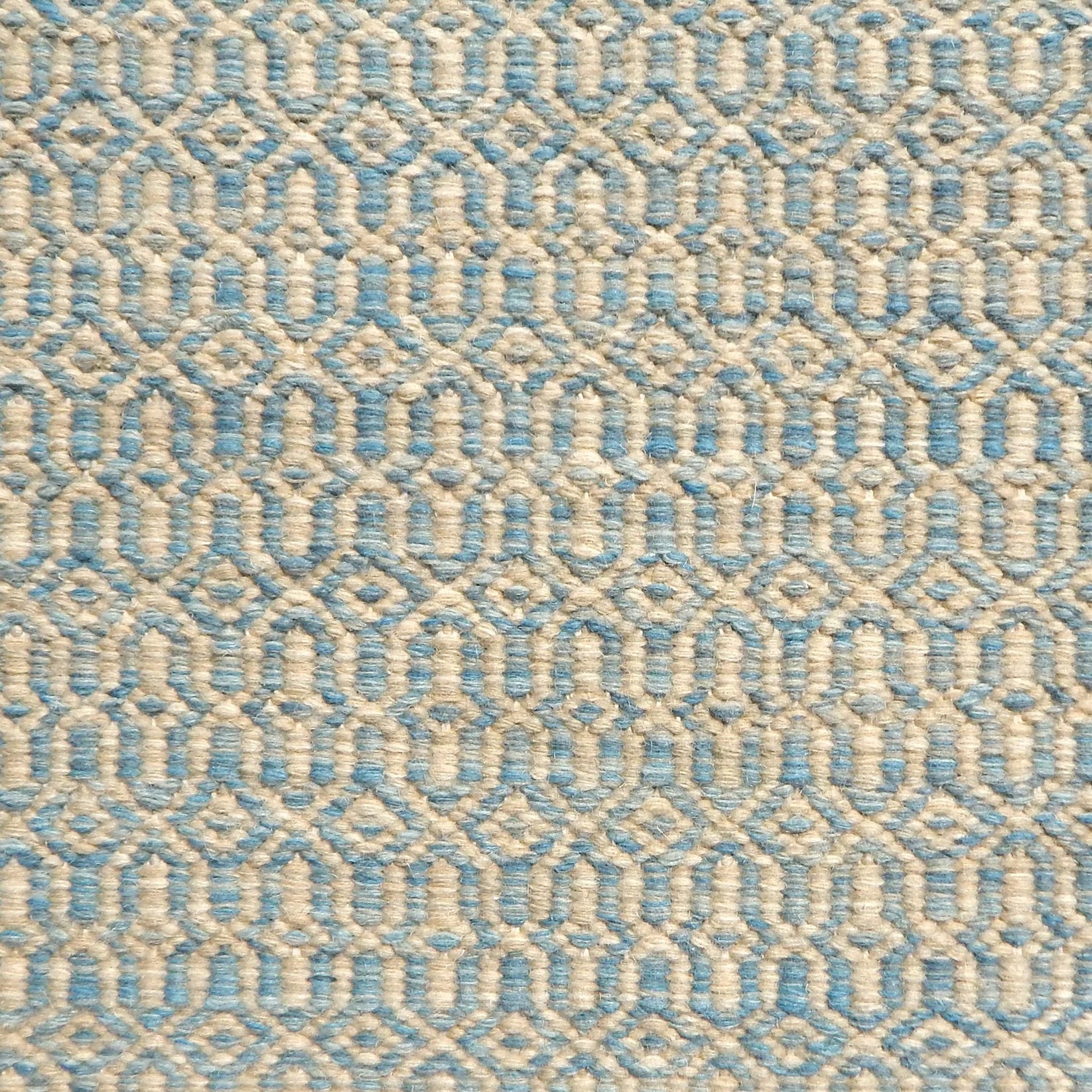 Detail of handwoven rug in an small scale geometric design in beige and blue. 