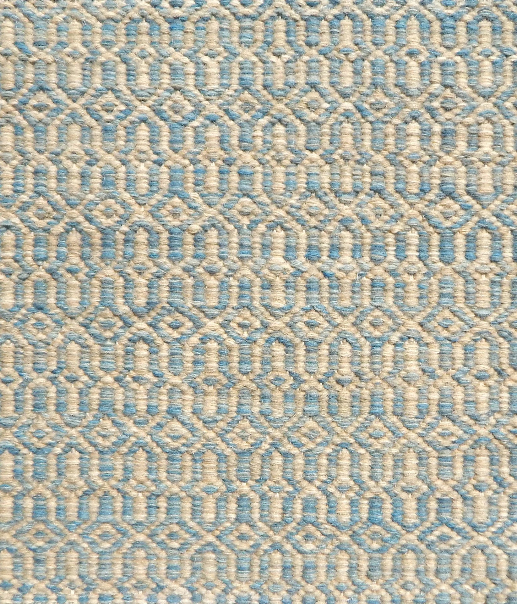 Detail of handwoven rug in an small scale geometric design in beige and blue. 