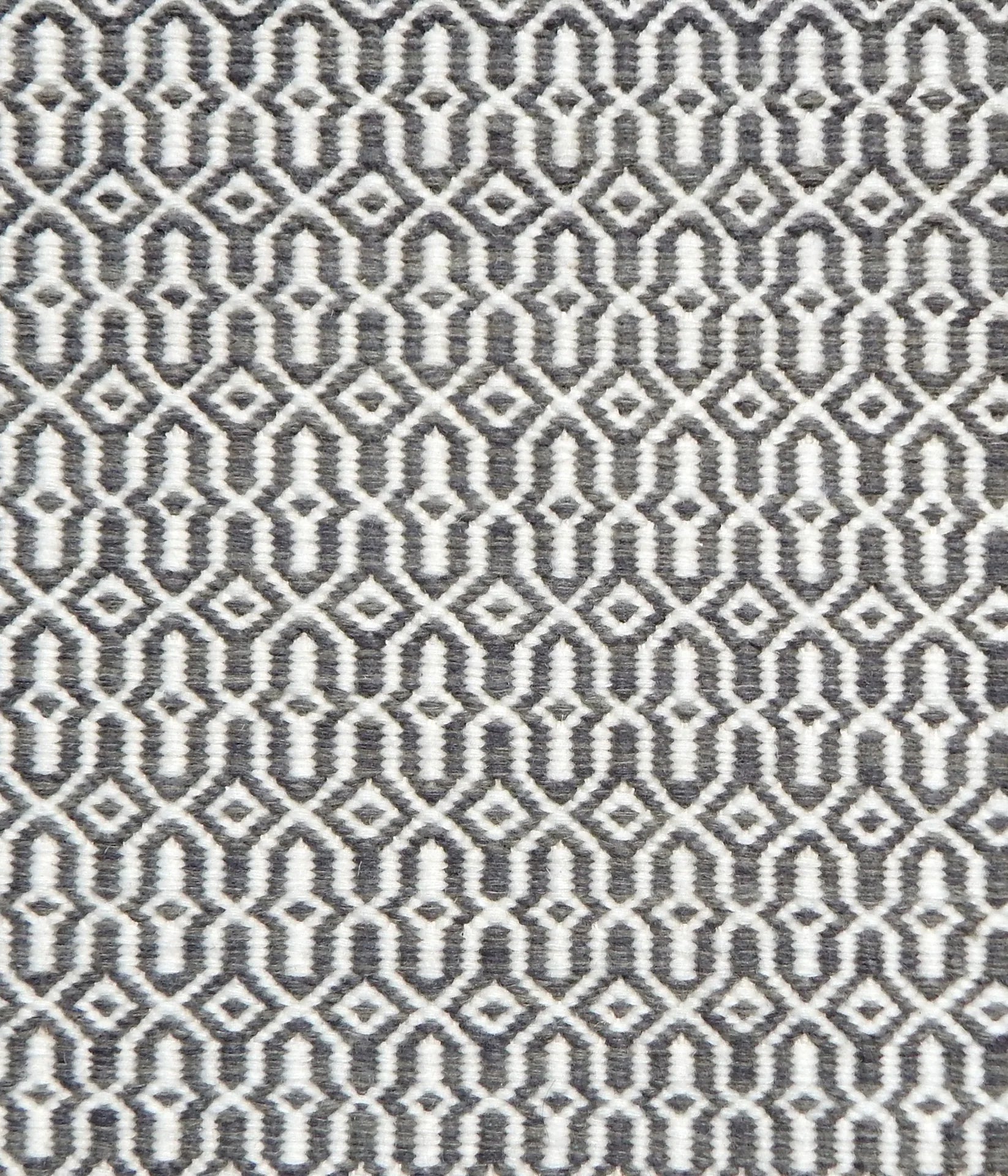 Detail of handwoven rug in an small scale geometric design in white and grey
