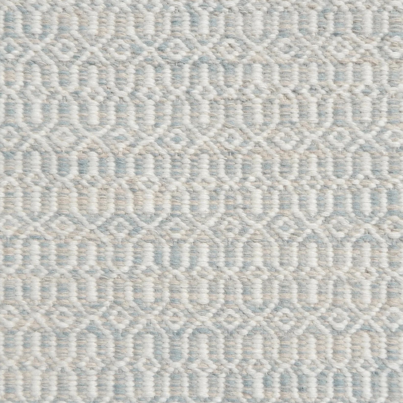 Detail of handwoven rug in an small scale geometric design in white and pale grey-blue