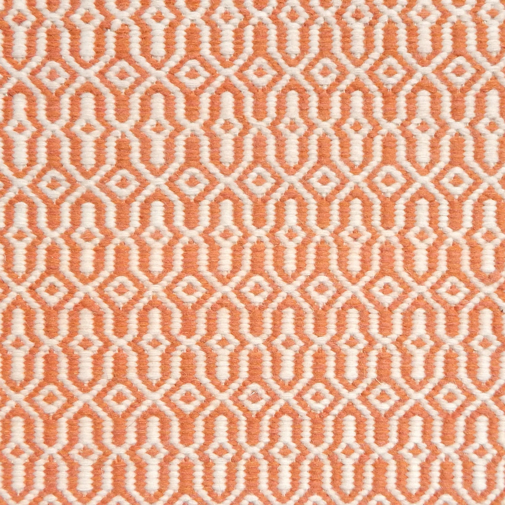 Detail of handwoven rug in an small scale geometric design in white and orange. 