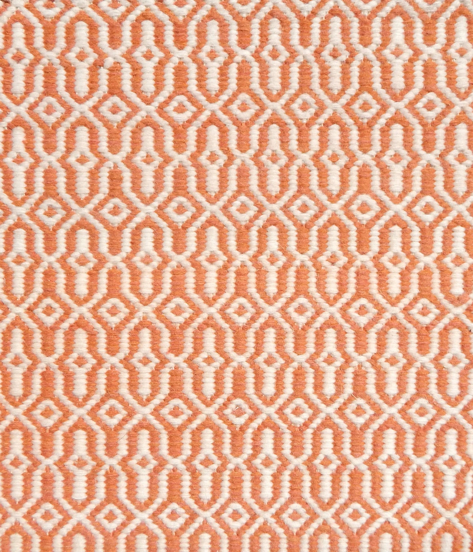 Detail of handwoven rug in an small scale geometric design in white and orange. 