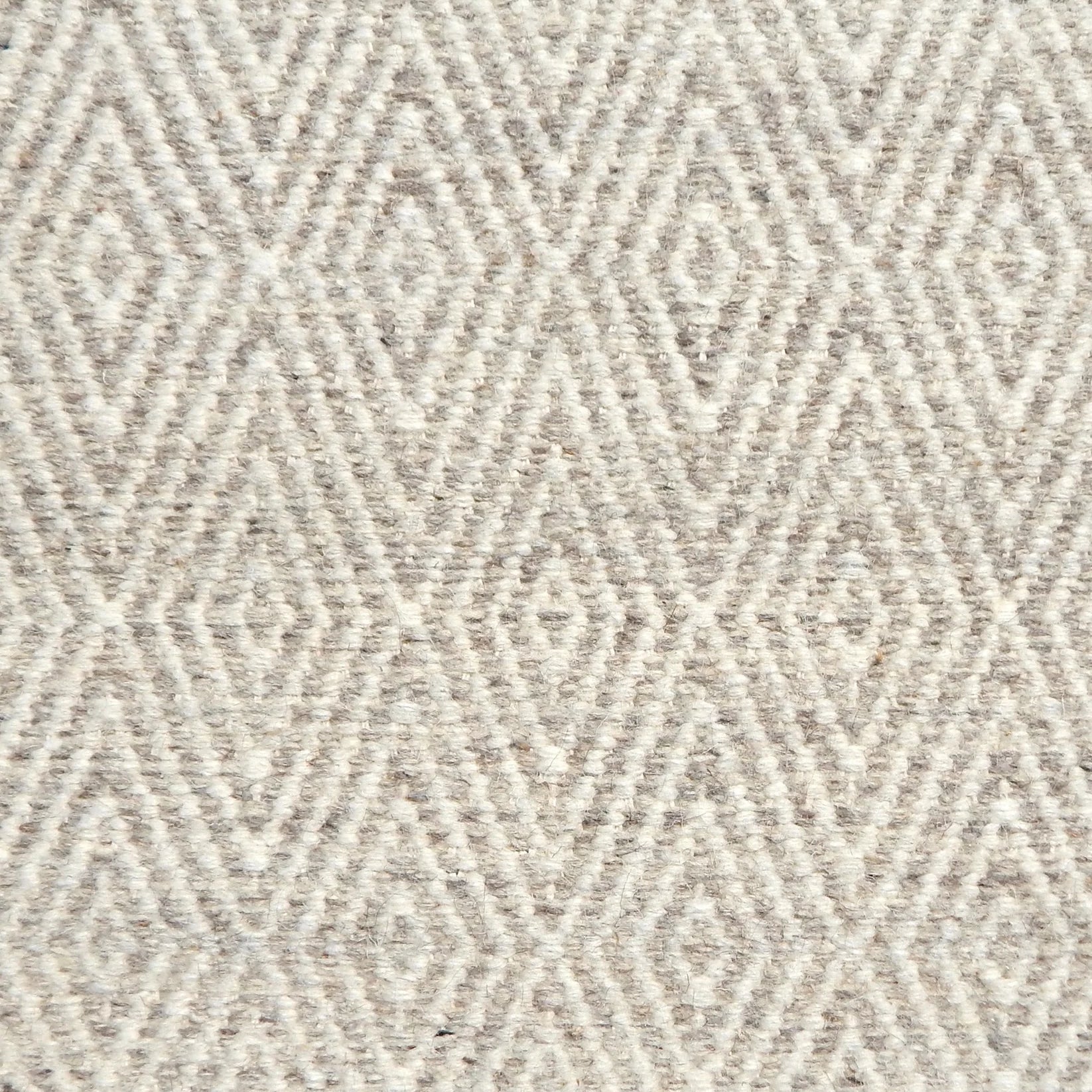 Flatwoven rug detail with a cream and grey diamond pattern.