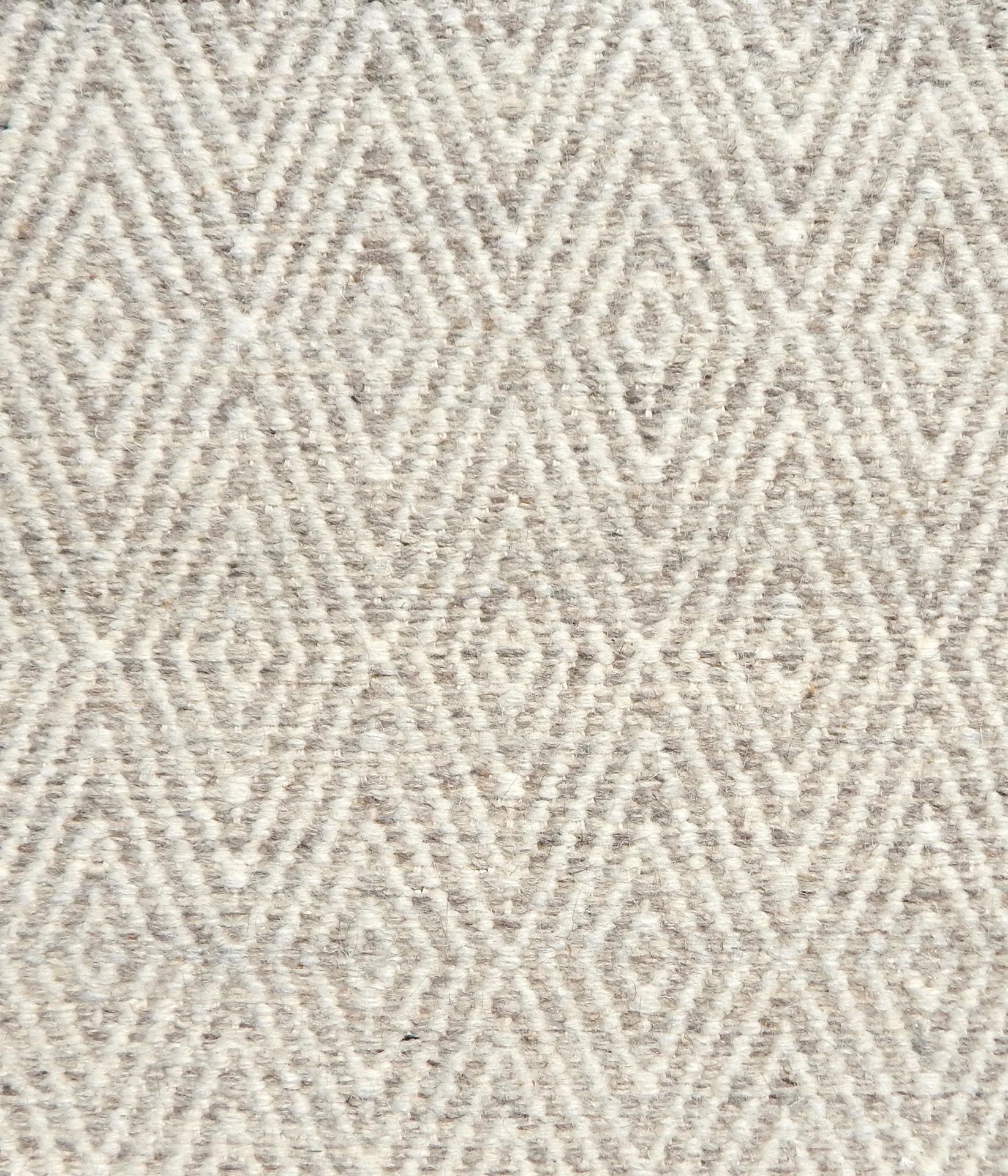 Flatwoven rug detail with a cream and grey diamond pattern.