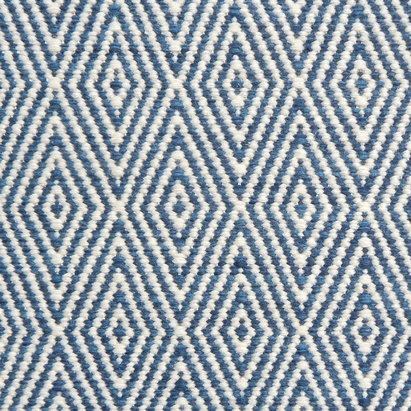 Flatwoven rug detail with a cream and blue diamond pattern.