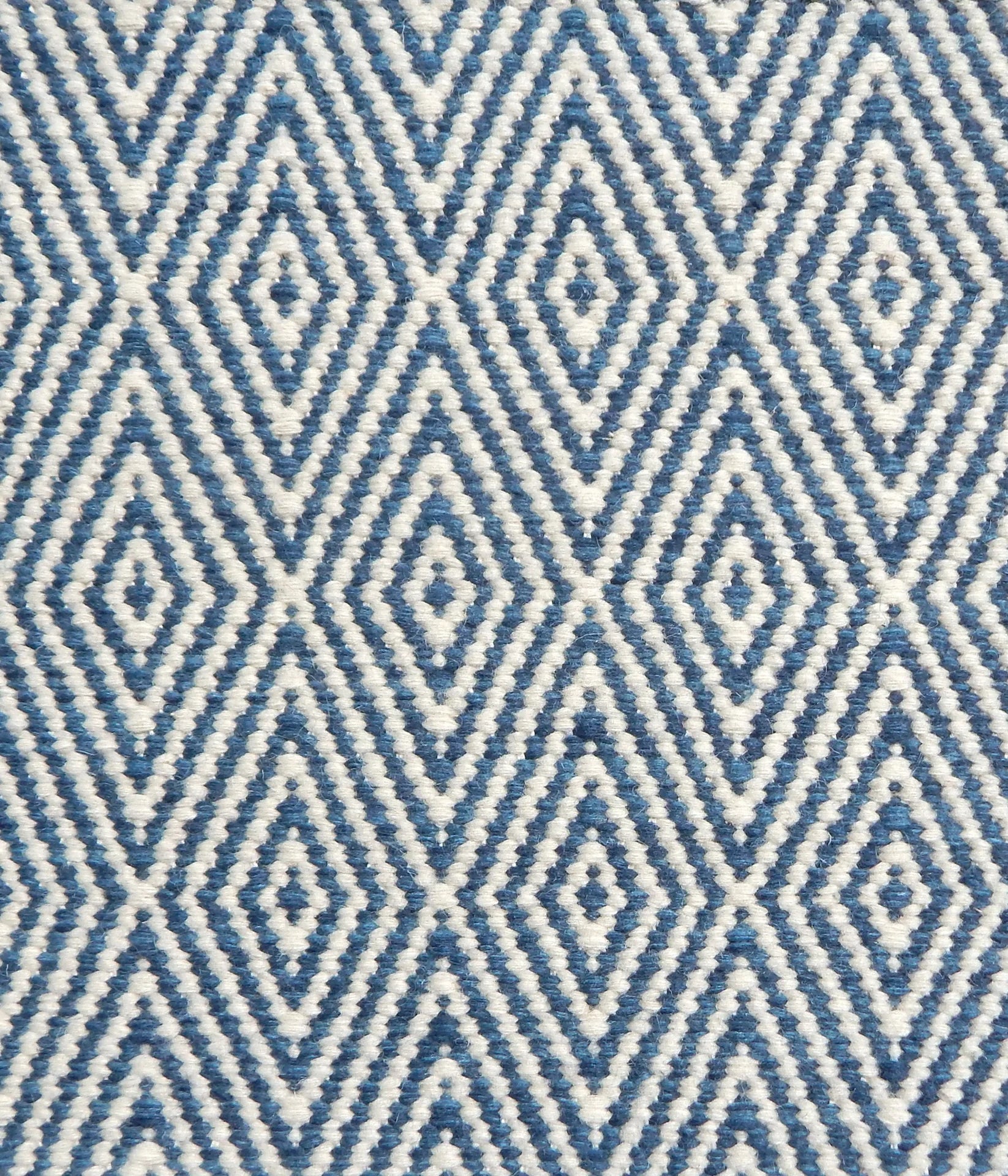 Flatwoven rug detail with a cream and blue diamond pattern.