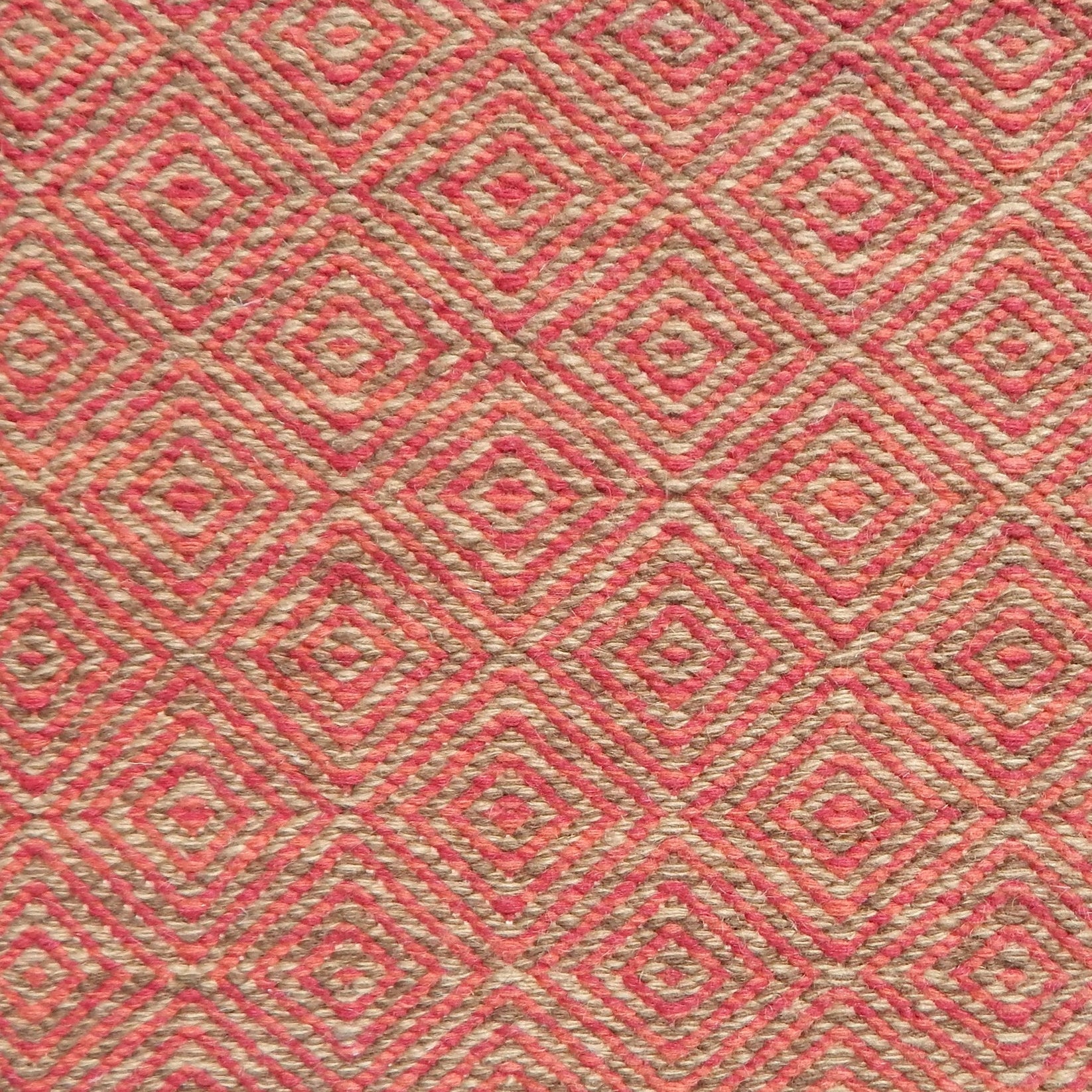 Flatwoven rug detail with a coral red and beige diamond pattern.