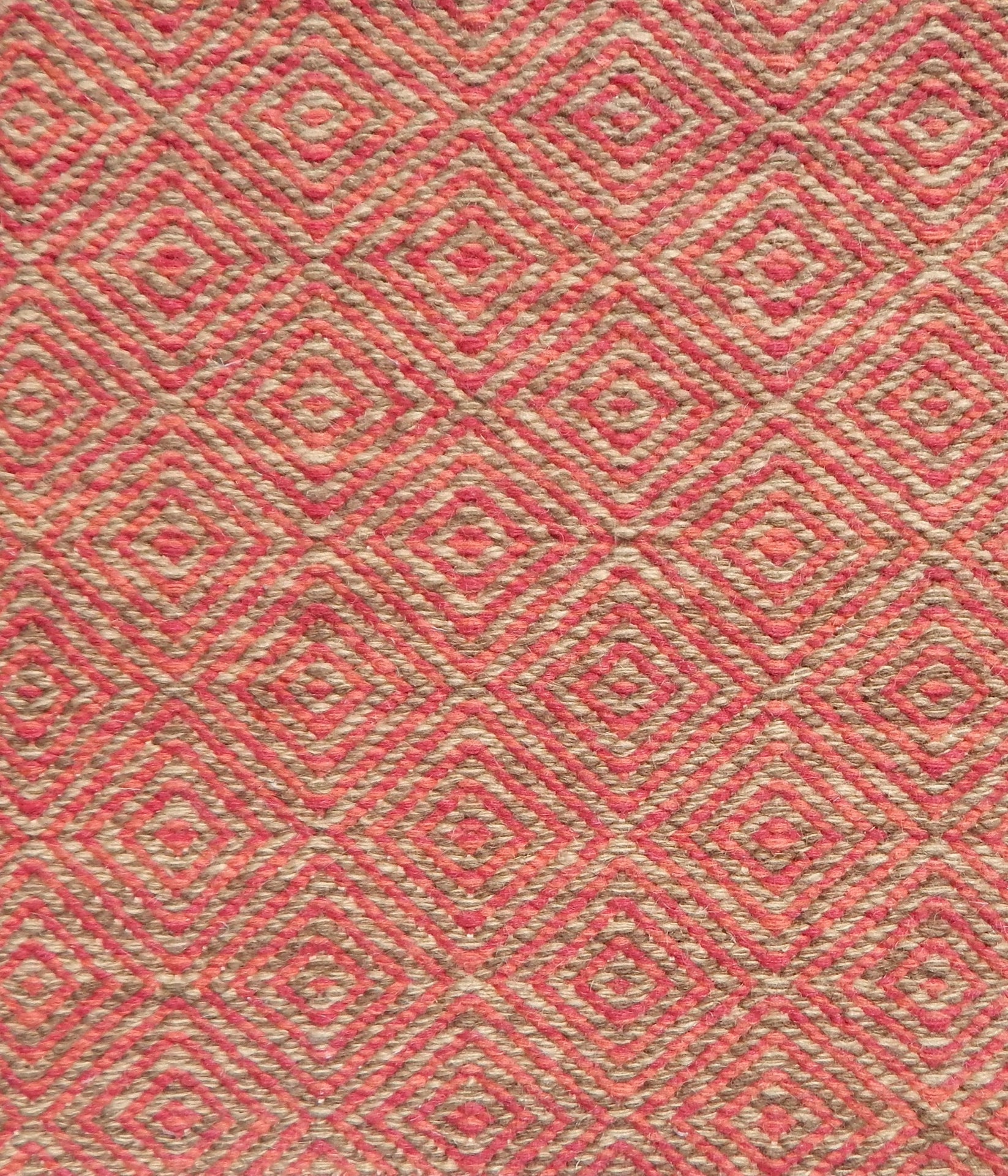 Flatwoven rug detail with a coral red and beige diamond pattern.