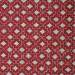 Detail of fabric in a geometric grid print in white on a red field.