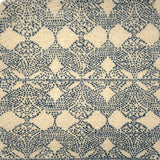 Handknotted rug with dotted geometric motif in blue on a cream field. 