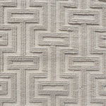 A close-up of a handwoven carpet with a repeating geometric maze in off white. 