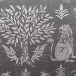 Close-up of fabric in a lion and plant print in white on a mottled gray field.