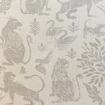 Close-up of fabric in a lion and plant print in gray on a mottled cream field.