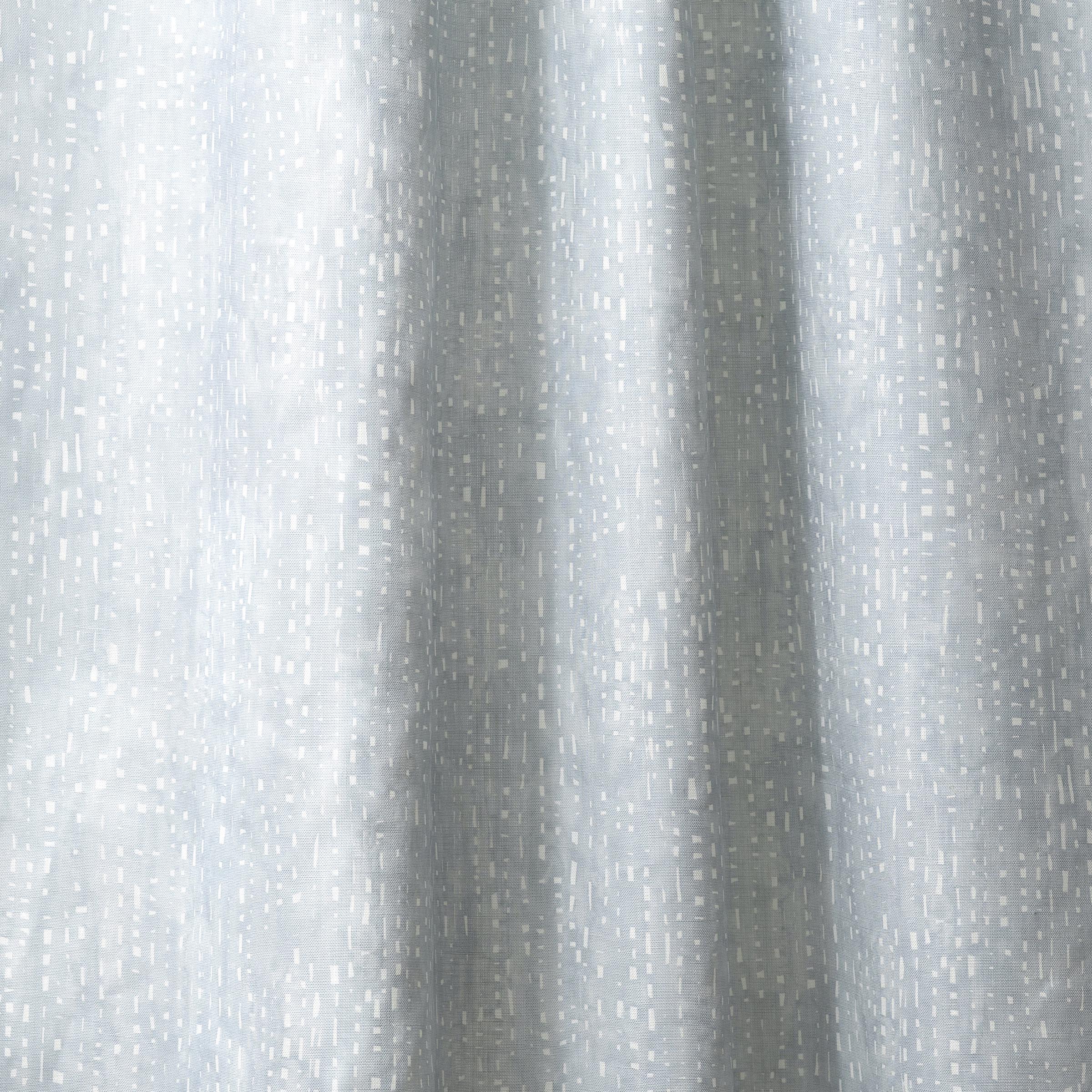 Draped linen in a painterly small-scale dashed dot print in white on a soft grey blue watercolor field.
