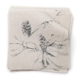 A stack of fabric swatches in a painterly pine cone and branch print in gray on a greige field.