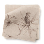 A stack of fabric swatches in a painterly pine cone and branch print in brown on a cream field.