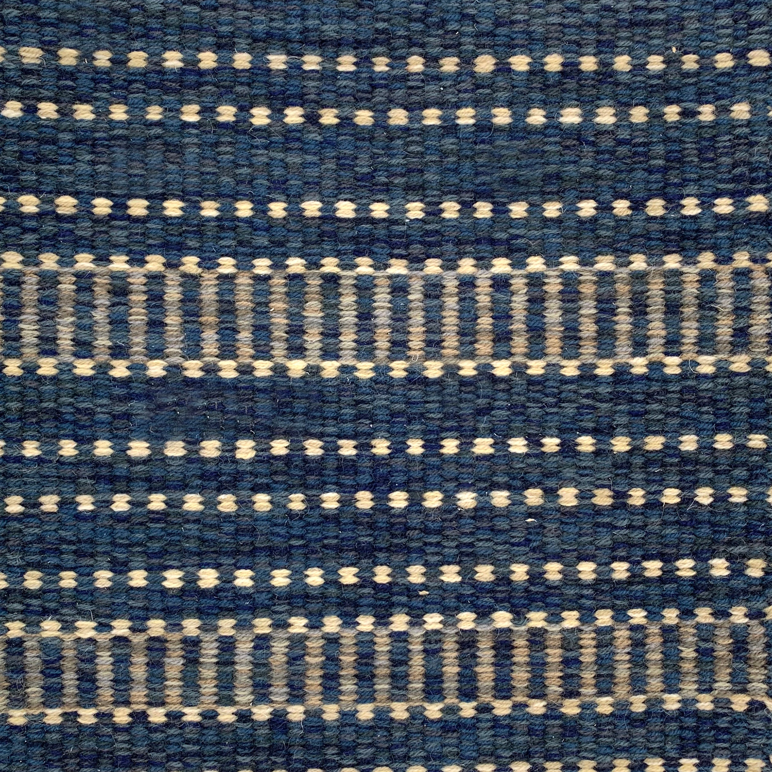 Handwoven rug detail in a spotted stripe design in blue and beige