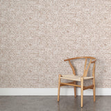 A wooden chair stands in front of a wall papered in a linear check pattern in shades of brown on a cream field.