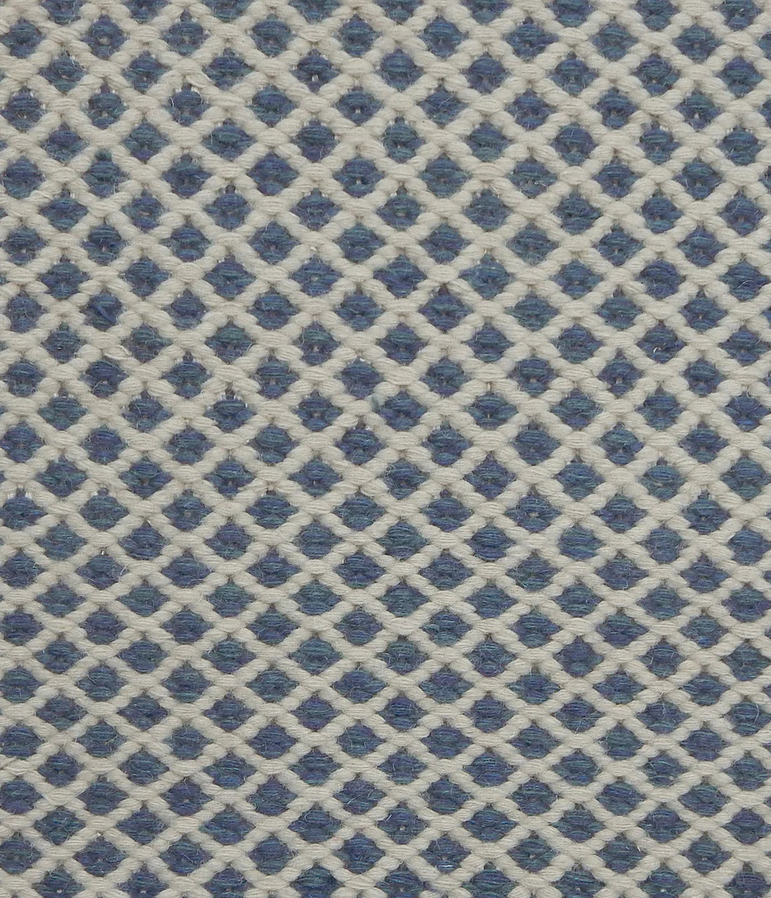 Handwoven rug with small scale diamond lattice in white on a blue field. 