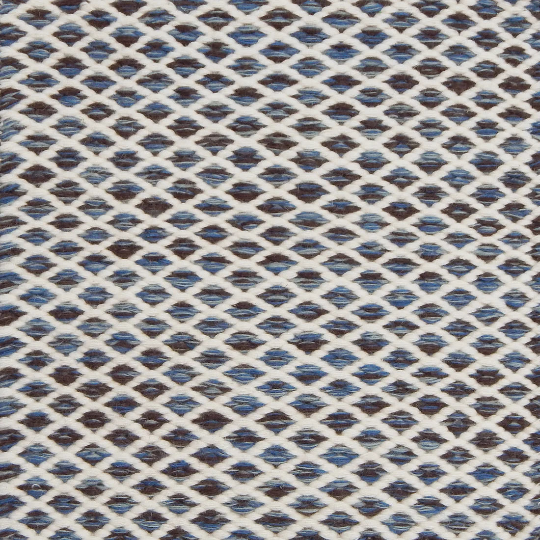 Handwoven rug with small scale diamond lattice in cream on a blue and brown field. 