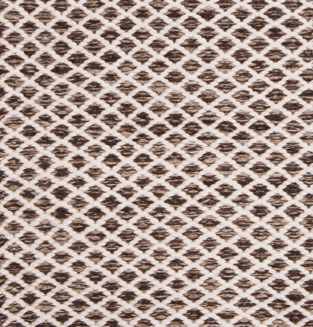 Handwoven rug with small scale diamond lattice in cream on a brown field. 