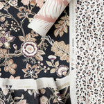 Styled flat-lay featuring a dark floral vine pattern in fabric and wallpaper paired with a roll of tropical print wallpaper in blush and white layered over a black and blush pink leopard print wallpaper. 
