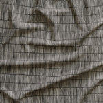Close up of gently draped printed linen with thin hand drawn stripe grid in ivory on black.