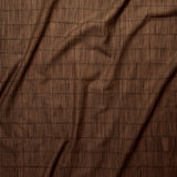 Close up of gently draped printed linen with thin hand drawn stripe grid in tonal brown.