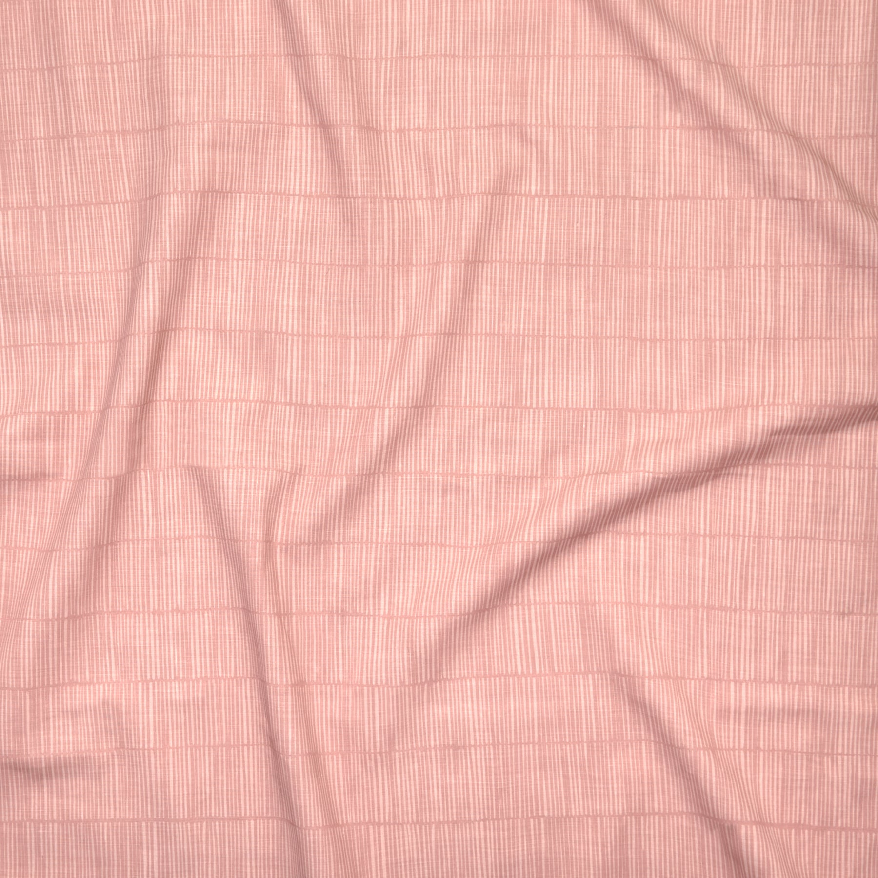 Close up of gently draped printed linen with thin hand drawn stripe grid in tonal pink.