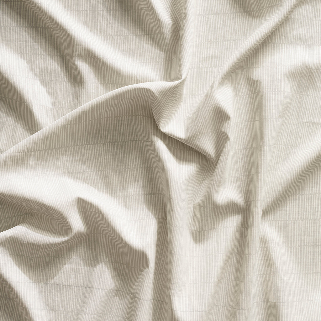 Close up of gently draped printed linen with thin hand drawn stripe grid in white on cream.
