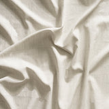 Close up of gently draped printed linen with thin hand drawn stripe grid in white on cream.