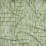 Close up of gently draped printed linen with thin hand drawn stripe grid in ivory on grass green.