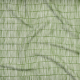 Close up of gently draped printed linen with thin hand drawn stripe grid in ivory on grass green.