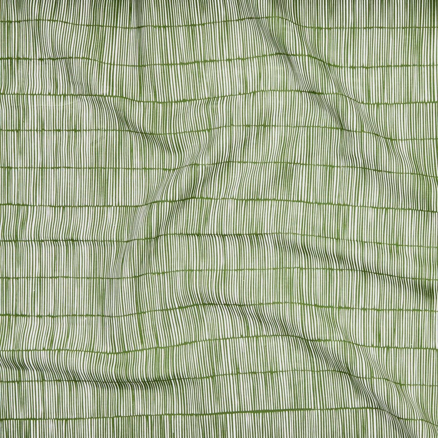 Close up of gently draped printed linen with thin hand drawn stripe grid in ivory on grass green.