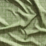 Close up of gently draped woven Indoor-Outdoor fabric with thin hand drawn stripe grid in ivory on grass green.