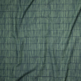 Close up of gently draped printed linen with thin hand drawn stripe grid in green on navy blue.