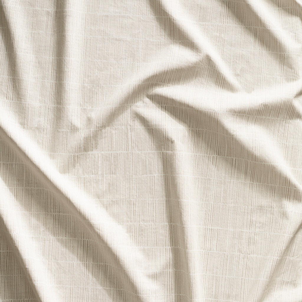 Close up of gently draped printed linen with thin hand drawn stripe grid in ivory on taupe.